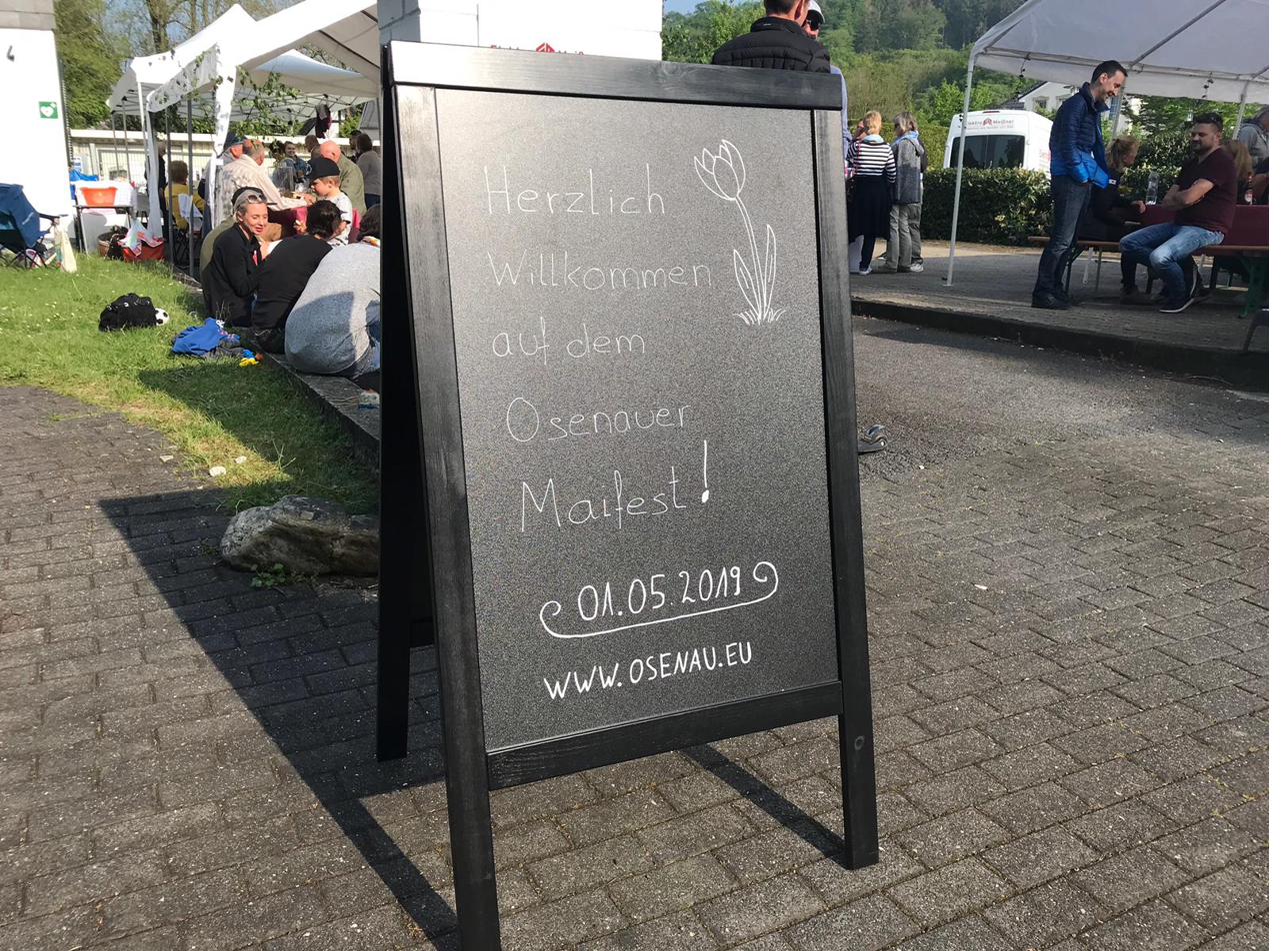 Schiefertafel mit der Aufschrift ‚Herzlich Willkommen auf dem Osenauer Maifest!‘